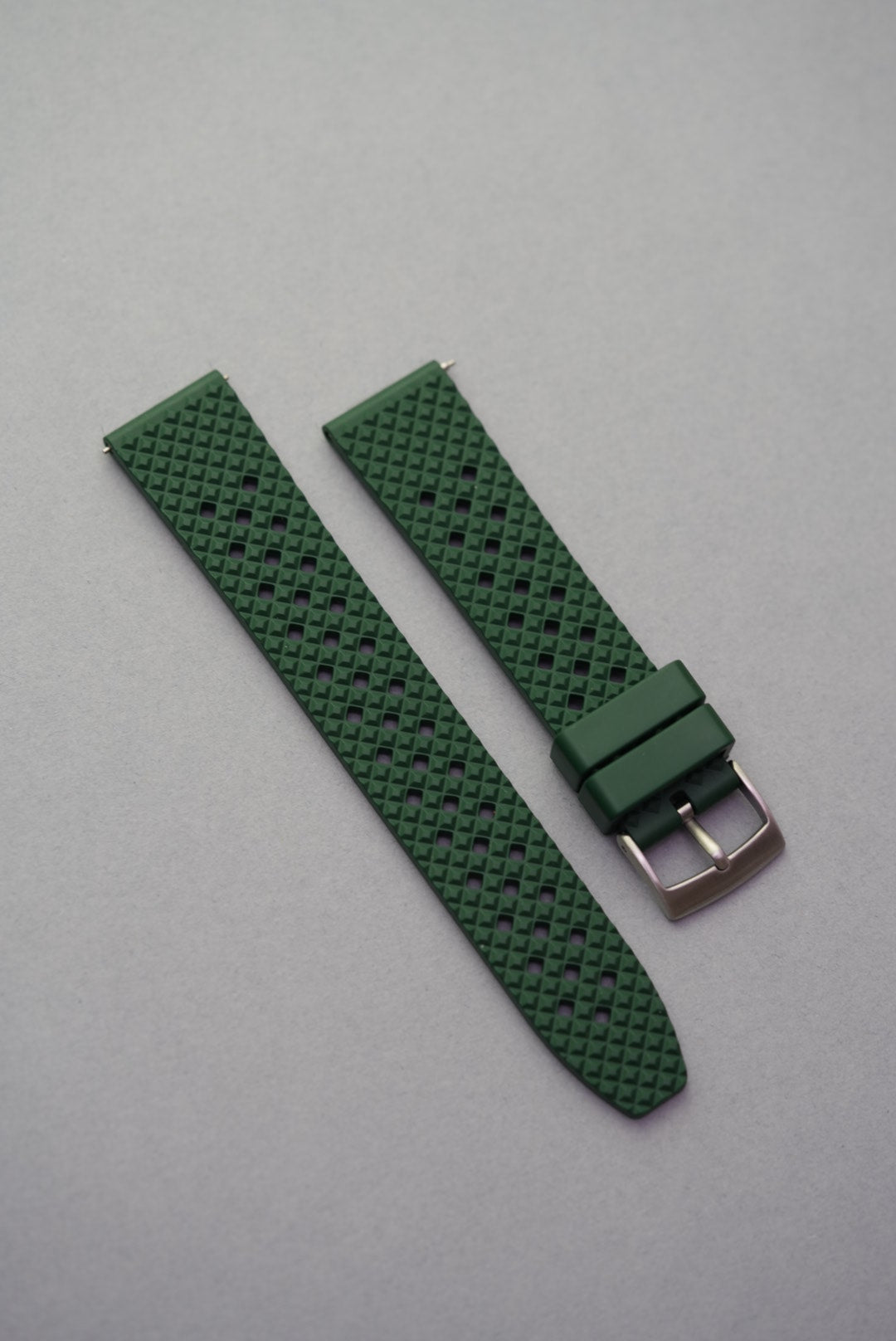 Green FKM rubber honeycomb-pattern watch strap with silver buckle, laid flat on a grey background