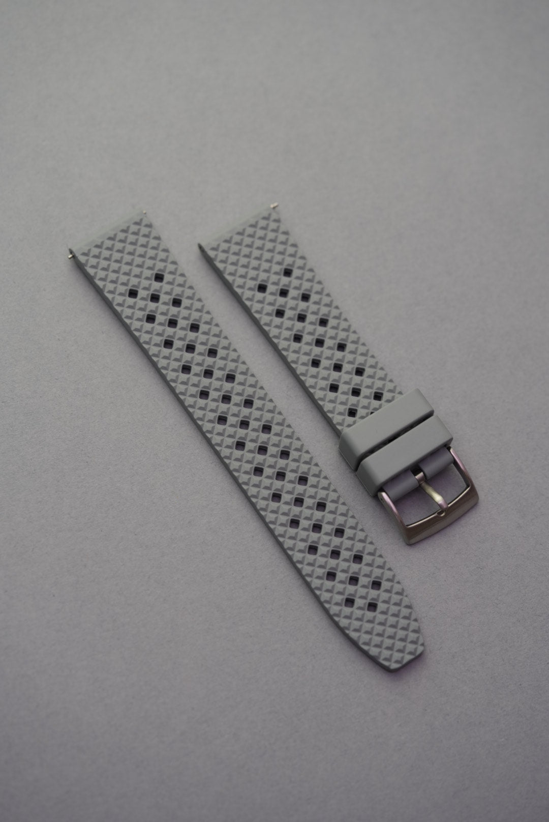 Light grey FKM rubber honeycomb-pattern watch strap with silver buckle, displayed on a grey surface.