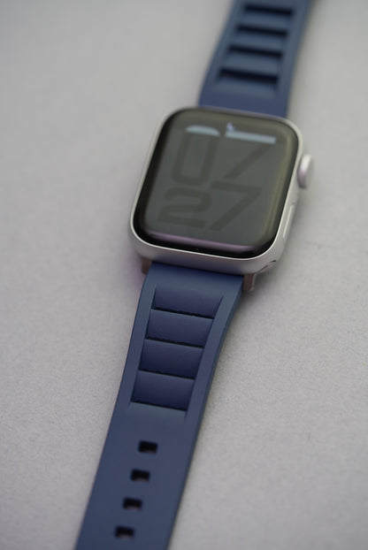 Apple Watch worn with navy FKM strap, photographed from an angle to highlight the strap’s vented design and fit.