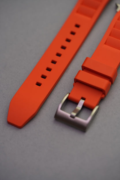 Close-up view of brushed buckle and strap loops on orange FKM Apple Watch strap.