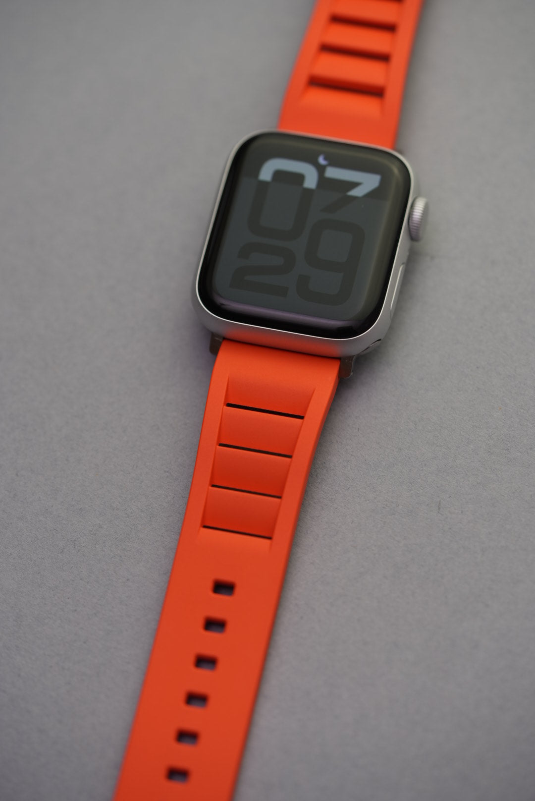 Apple Watch worn with bright orange vented FKM strap, angled wrist shot to highlight fit and colour.