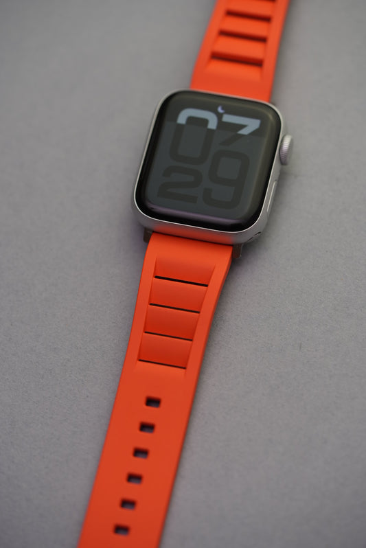 Apple Watch worn with bright orange vented FKM strap, angled wrist shot to highlight fit and colour.