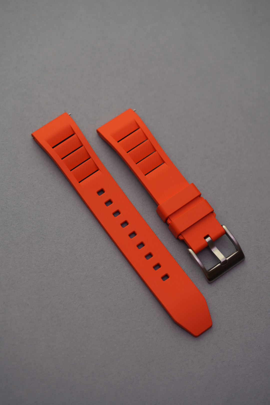 Bright orange FKM rubber watch strap with a vented design and brushed stainless steel buckle, perfect for sporty timepieces.