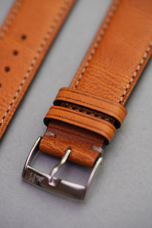 Close-up of golden brown fine grain calfskin leather watch strap with polished buckle