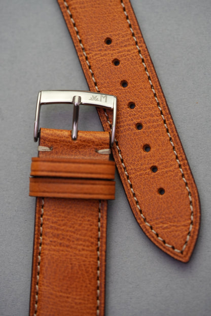 Polished stainless steel buckle on golden brown calfskin watch strap