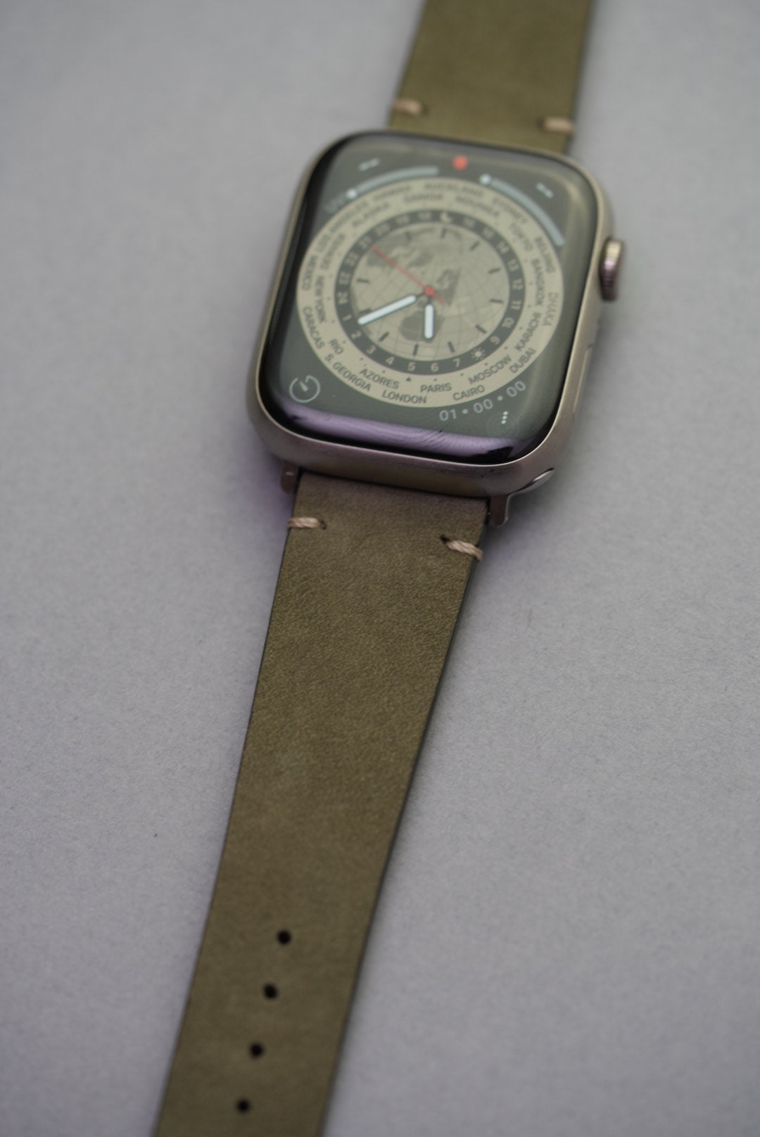 Close-up detail of green Apple Watch strap in calfskin leather with visible lug stitching