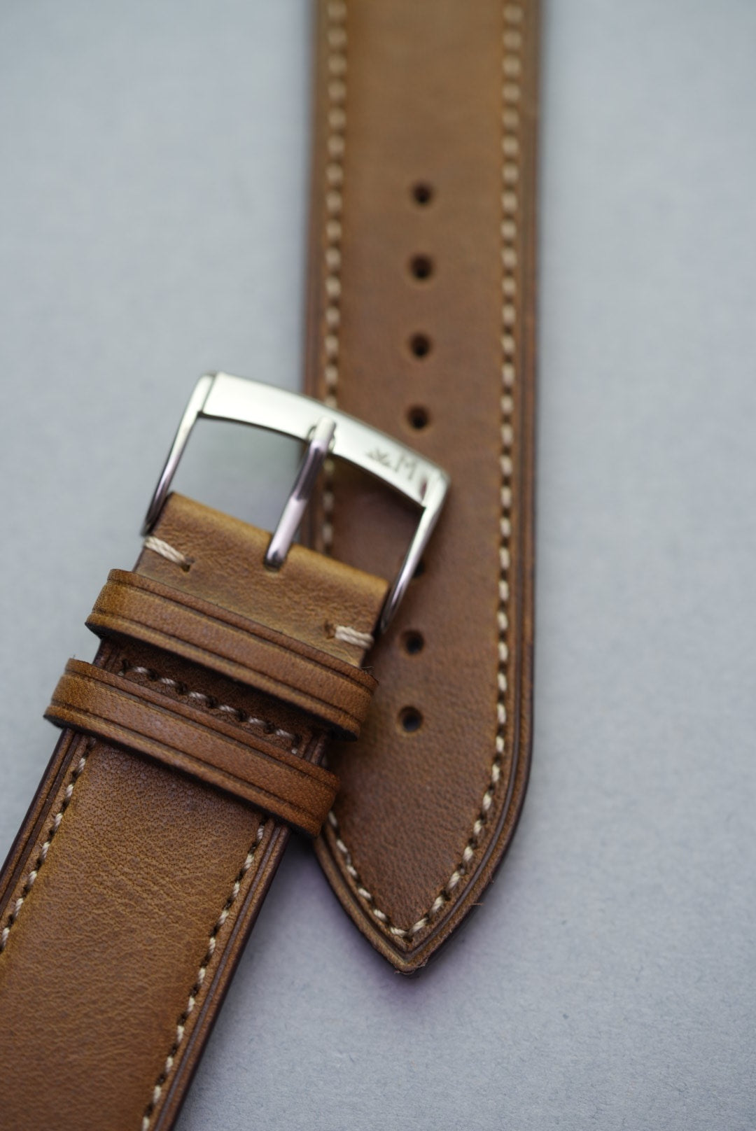 Close-up of green fine grain calfskin leather watch strap showing polished stainless steel buckle