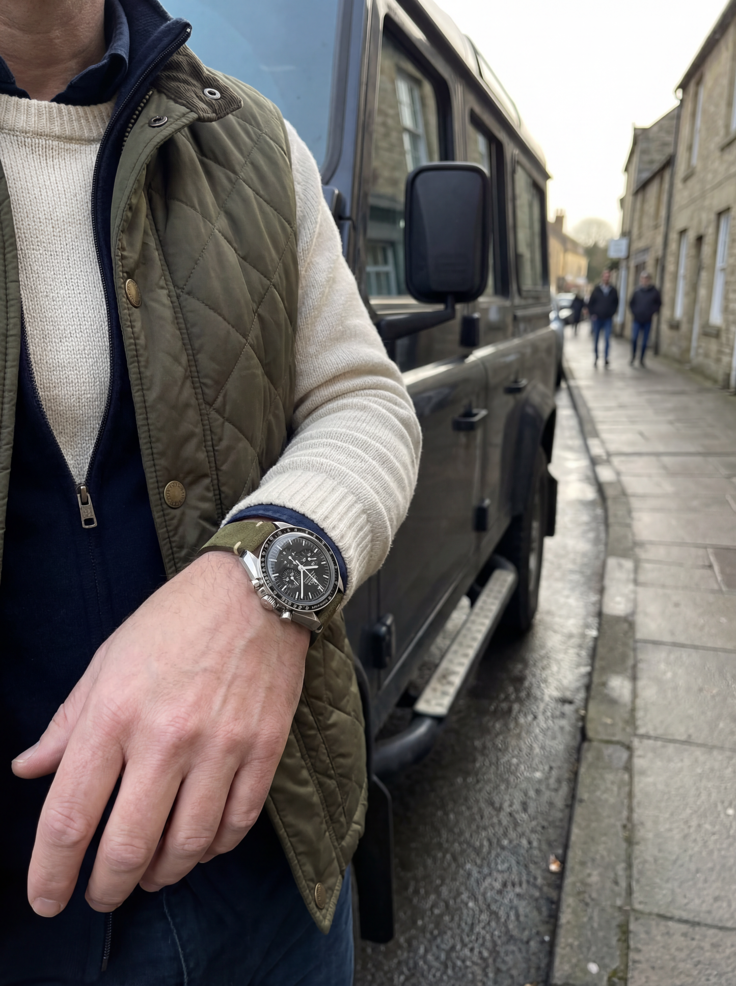 Person wearing a watch with a vehicle and people in the background