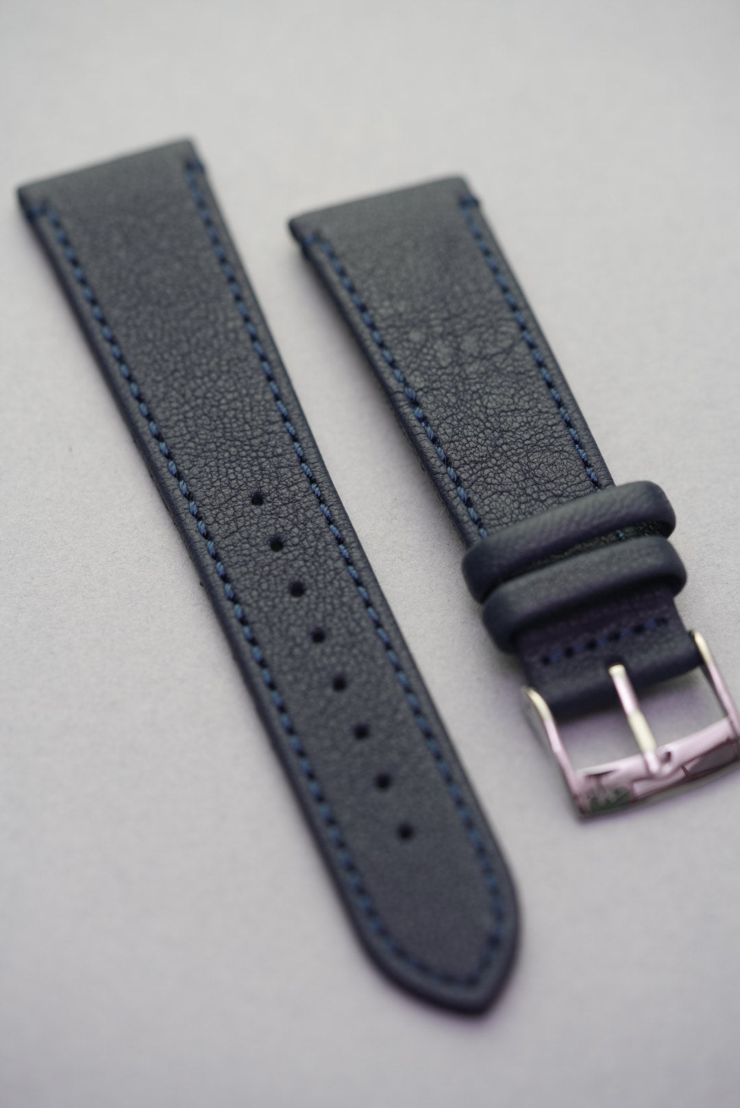 Macro detail of Midnight Capri strap showing fine sheepskin grain and navy blue stitching.