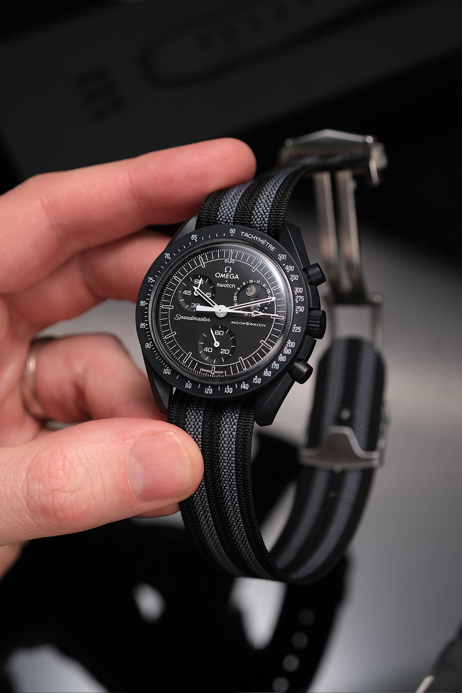 MoonSwatch nylon deployant strap in black and grey — fitted on Snoopy New Moon MoonSwatch, front view