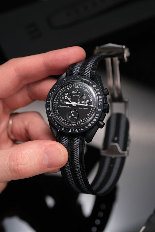 MoonSwatch nylon deployant strap in black and grey — fitted on Snoopy New Moon MoonSwatch, front view