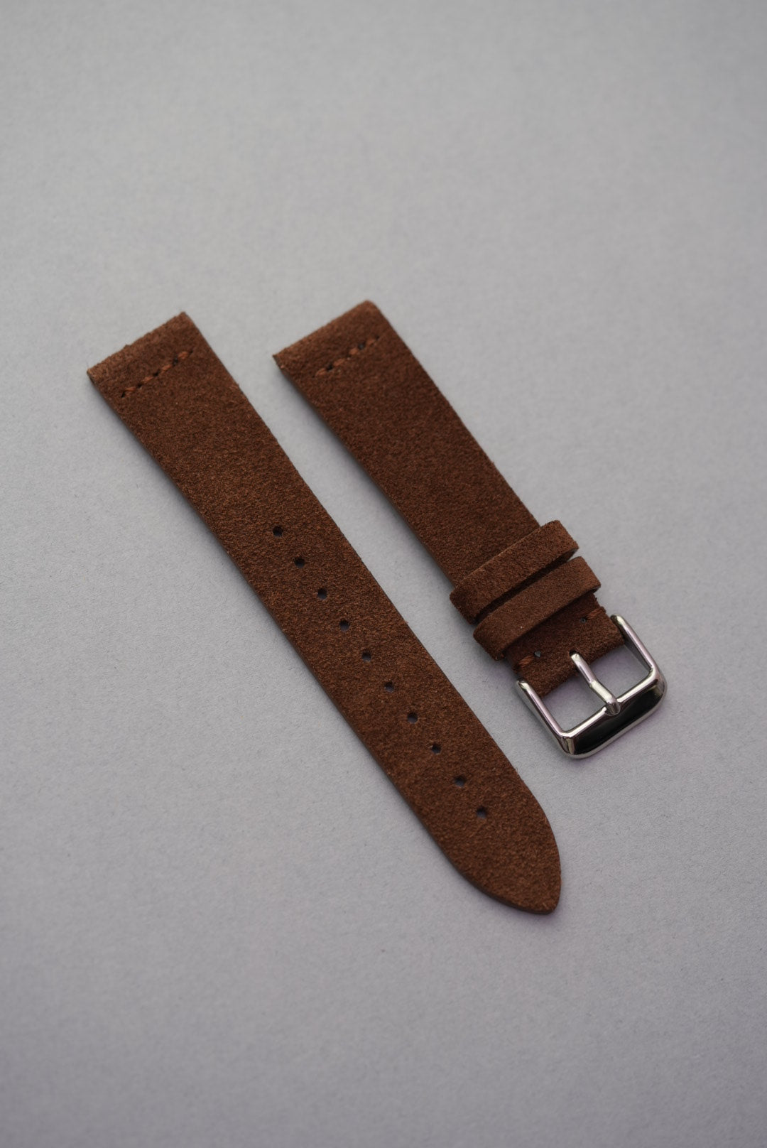 High-polished stainless steel buckle on brown suede MoonSwatch strap — close-up