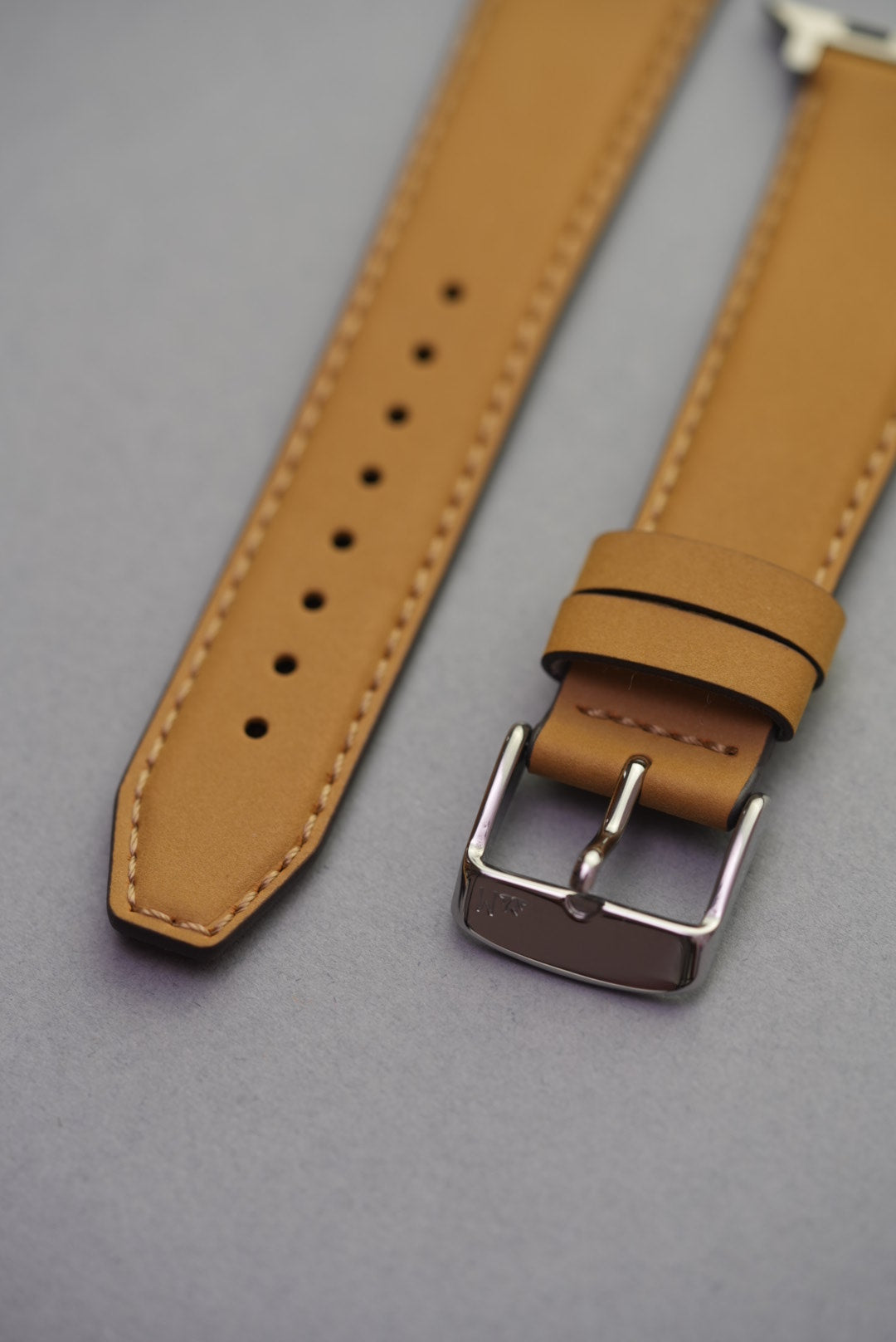 Tan nubuck leather strap fitted on an Apple Watch with silver buckle and natural contrast stitching.