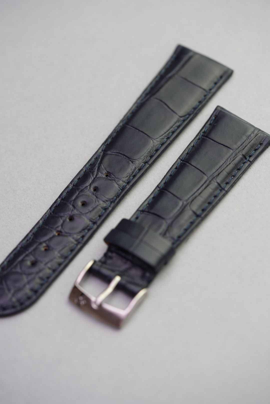 Angled front view of navy alligator grain strap showing full texture and stitching