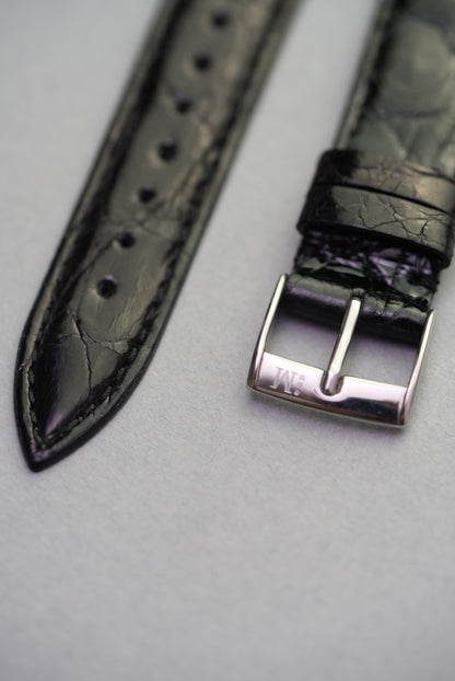 Detail shot of the polished stainless steel buckle and pointed tip on the Noir crocodile strap, designed for Cartier.