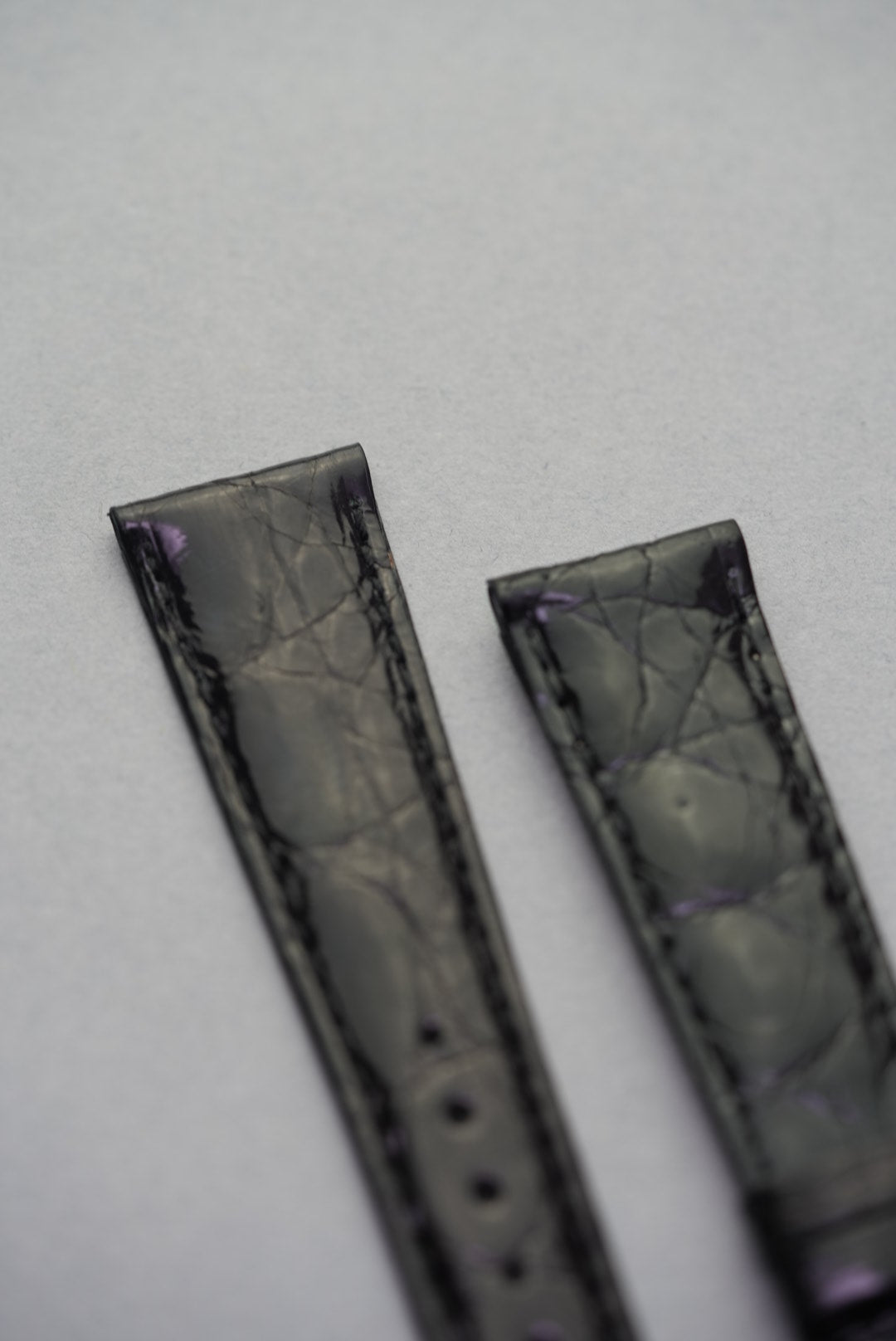 Close-up of the upper ends of the Noir crocodile leather strap for Cartier, showing rich scale definition and deep gloss.