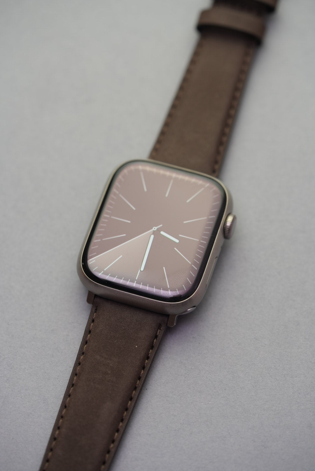 Brown nubuck strap on Apple Watch, showing matte texture and precision stitching.