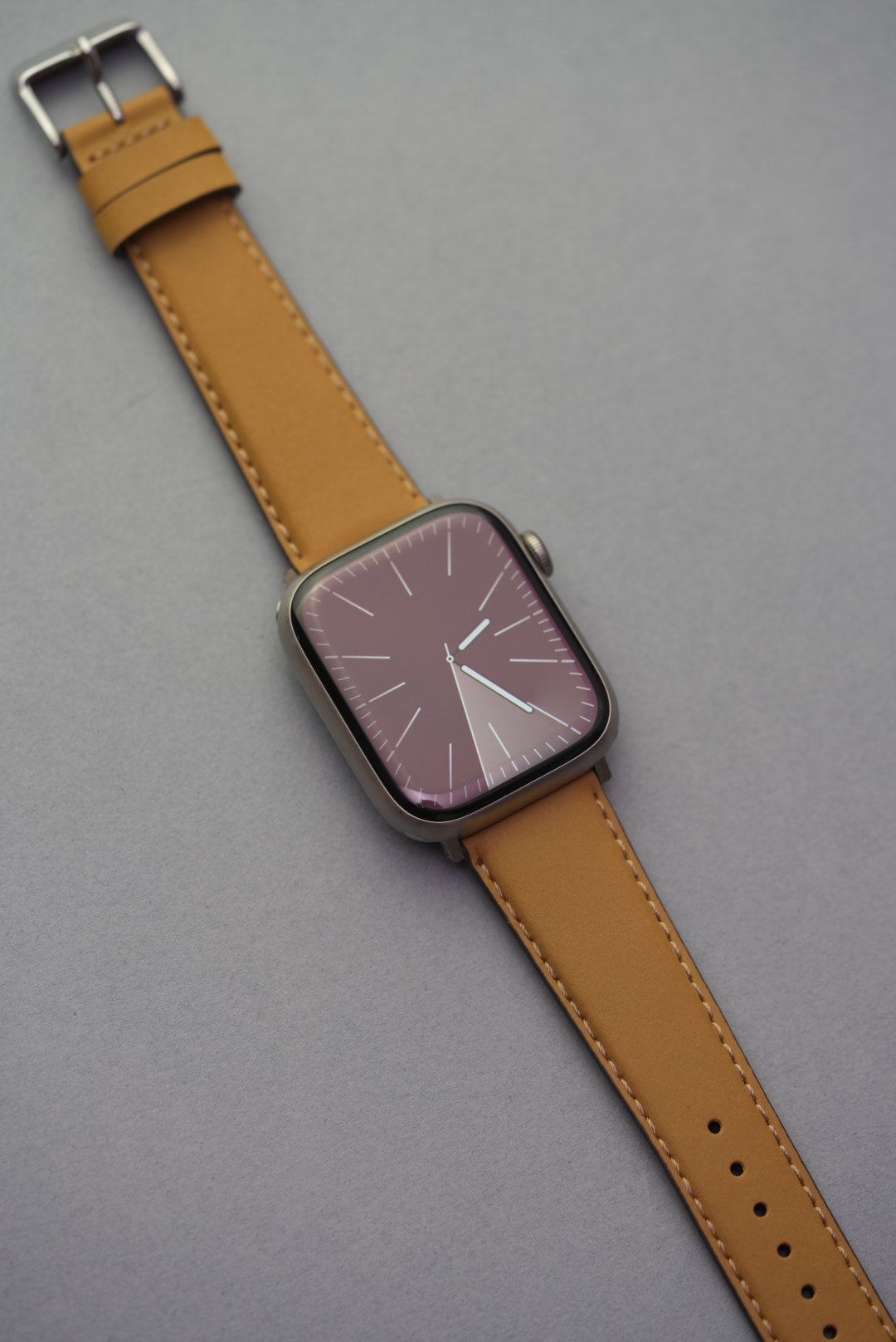 mustard buck Apple Watch strap with polished silver buckle and visible keeper loops, shown at angle.
