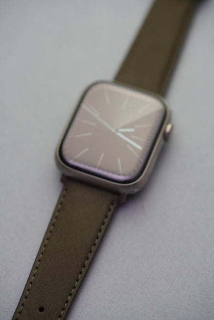 Close-up of olive nubuck strap for Apple Watch with contrast stitching and fine leather grain.
