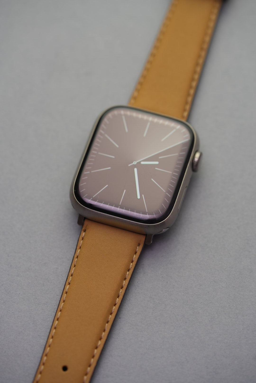 Mustard nubuck leather strap fitted on an Apple Watch with silver buckle and natural contrast stitching.