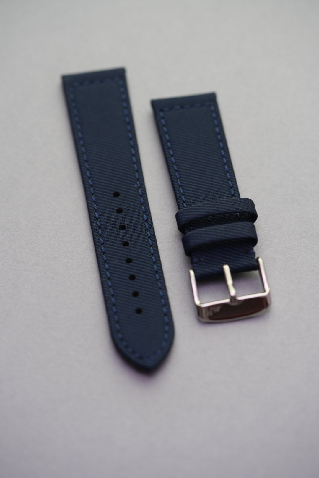 Full flat lay of the Ocean Blue gabardine strap with matching stitching and polished buckle.
