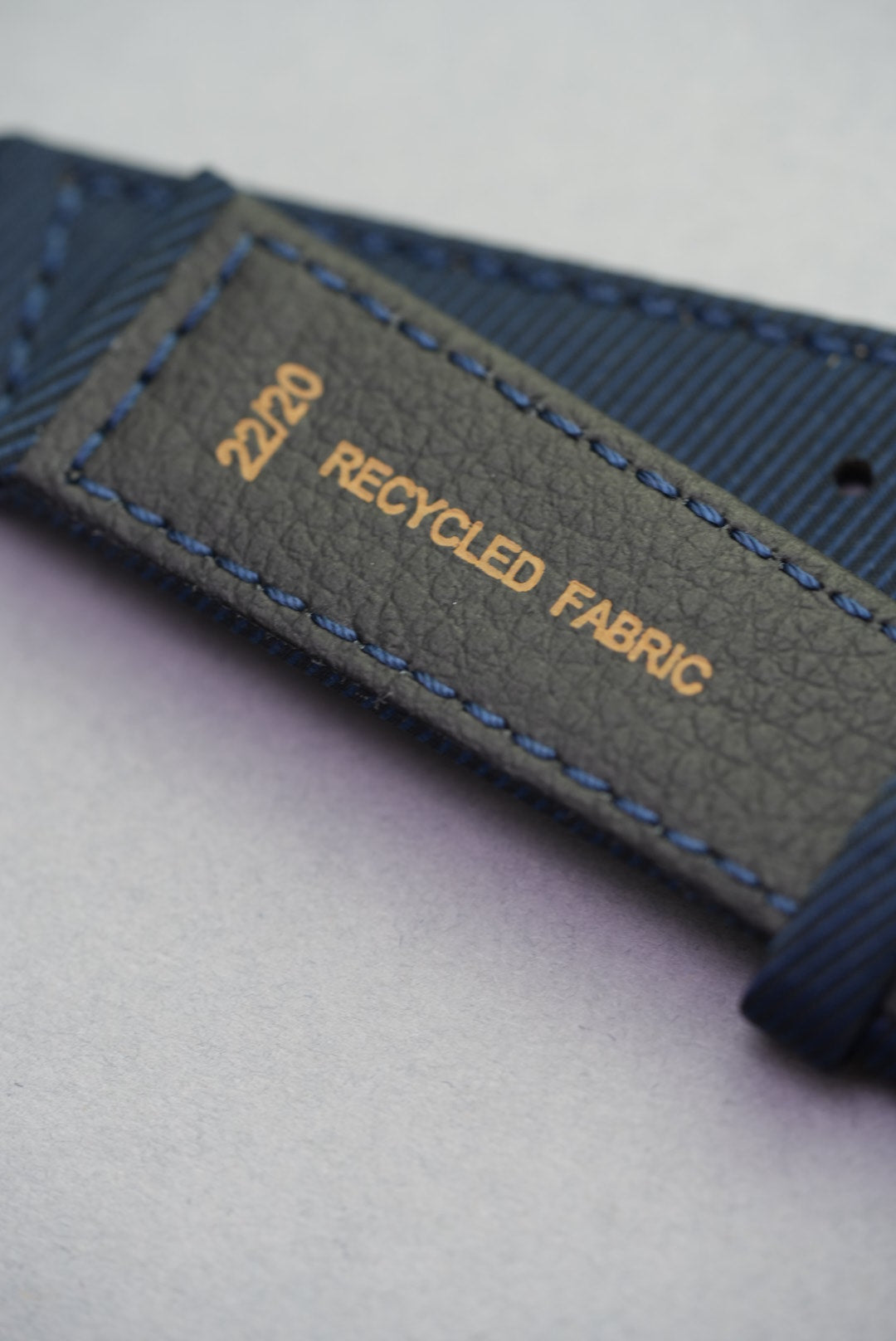 Underside of the Ocean Blue recycled fabric strap, showing size marking and textured backing with blue stitching.