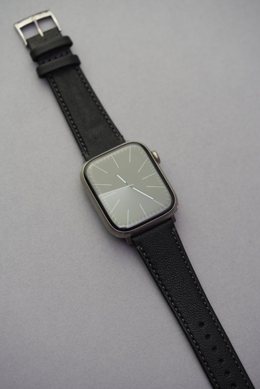 Piano Noir sheepskin strap fitted to Apple Watch, featuring rich matte black leather with tonal stitching.