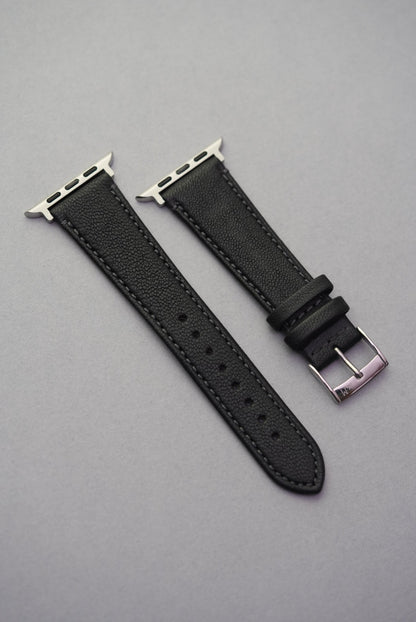 Full-length view of the Piano Noir Apple Watch strap in fine-grain sheepskin with polished buckle and adaptors.