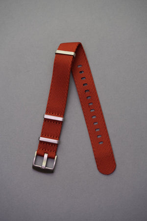 Premium copper fabric NATO watch strap with brushed stainless steel keepers, laid flat on grey background.