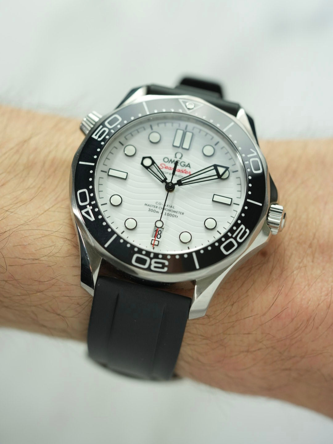 Wrist view of the Omega Seamaster, focusing on the polished buckle and strap detailing against a marble backdrop.