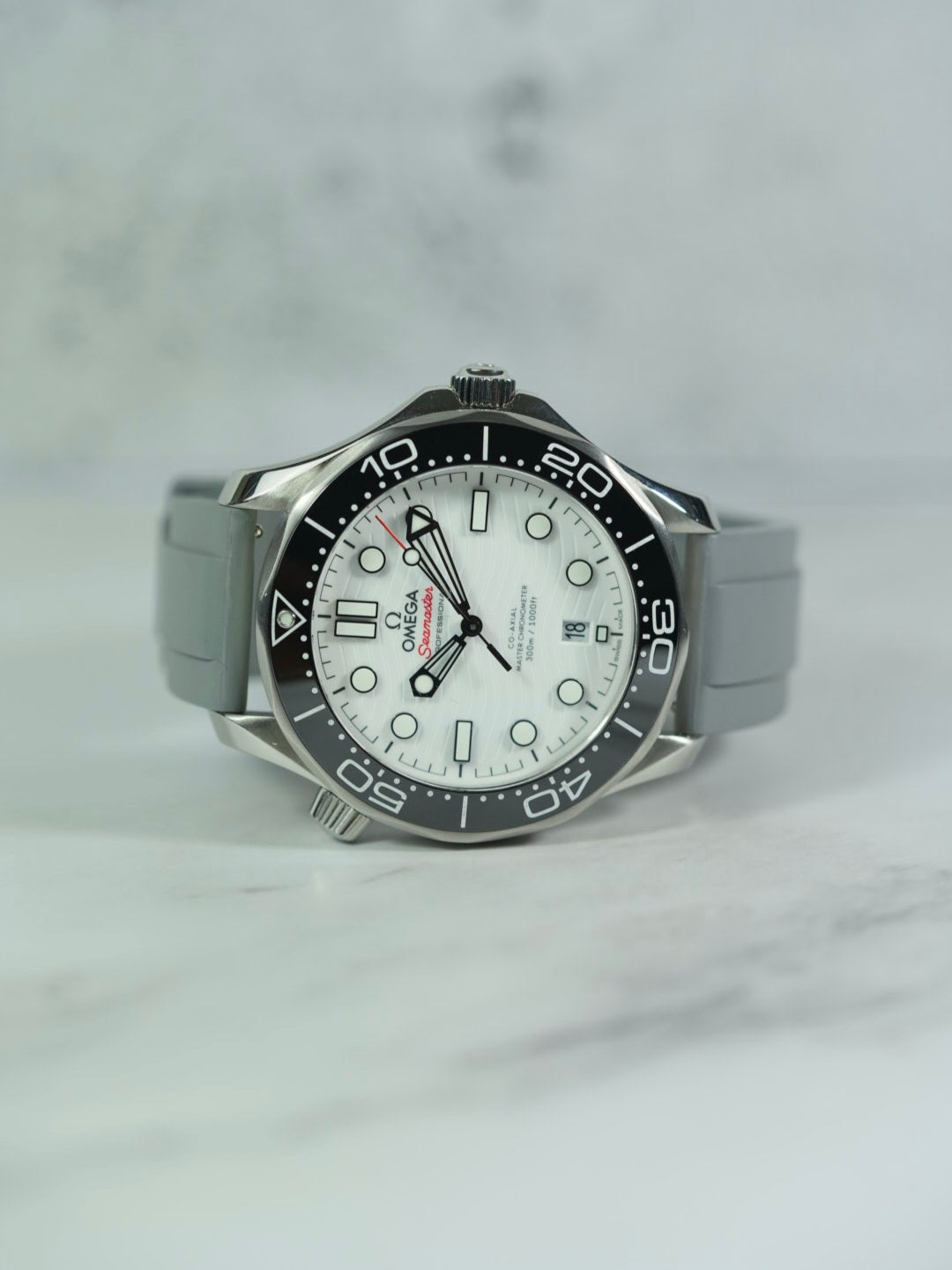 Front view of an Omega Seamaster watch with a GREY FKM rubber strap, showcasing its sleek design on a marble background.