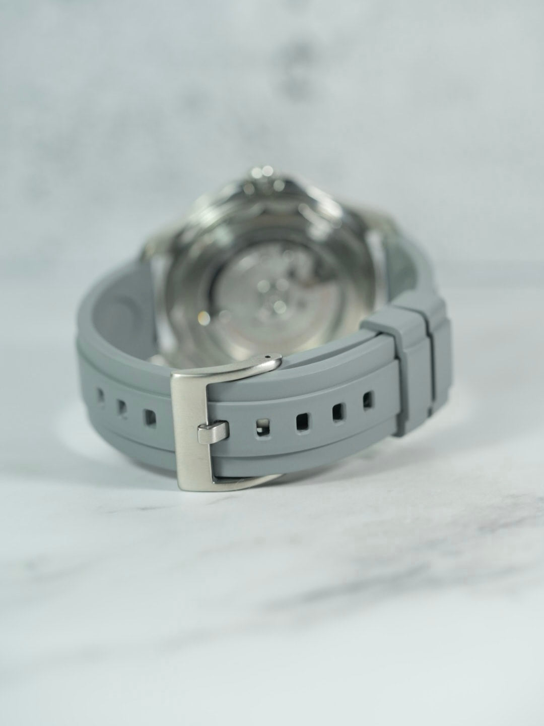 Rear view of the Omega Seamaster, focusing on the polished buckle and strap detailing against a marble backdrop.