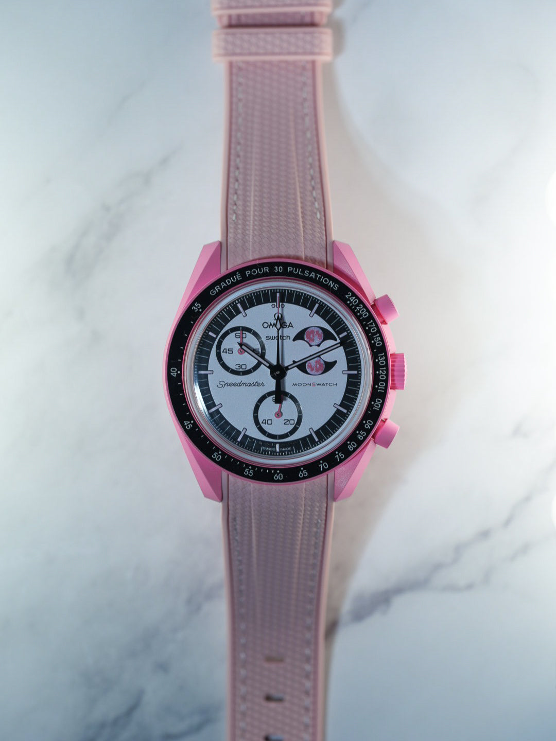 Flat lay of the Swatch x Omega MoonSwatch Mission to the Pink Moonphase with matching pink rubber strap and pink case – clean and uniform look.