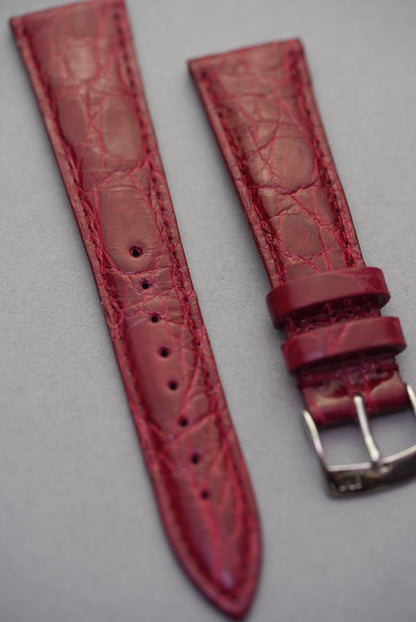Ruby red crocodile strap for Cartier laid diagonally, showcasing semi-matte finish and elegant taper.