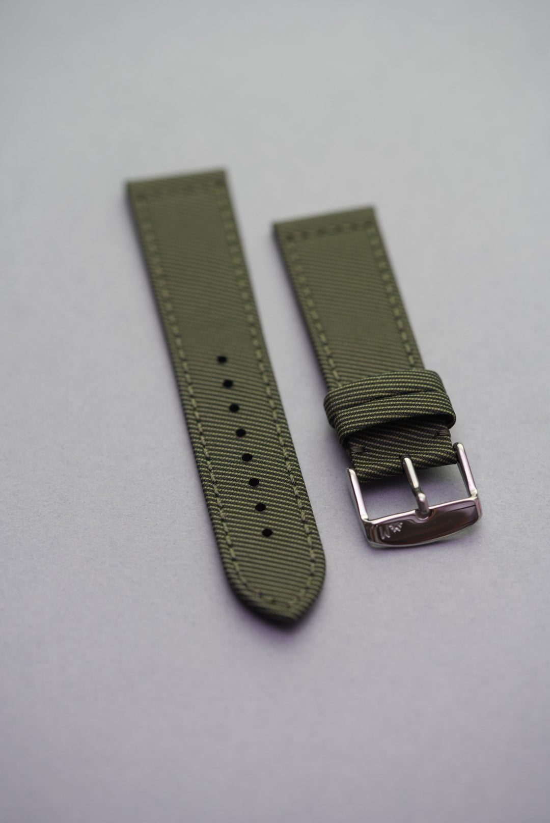 Full flat lay of the Sagebrush recycled gabardine watch strap, finished with tonal green stitching and a polished stainless steel buckle.