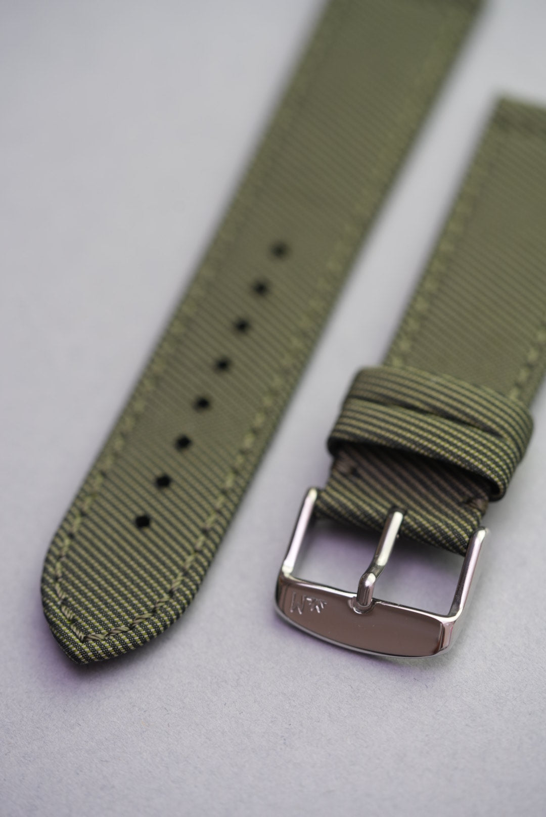 Close-up view of the Sagebrush fabric strap showing fine diagonal weave, punched holes, and buckle loop detail.