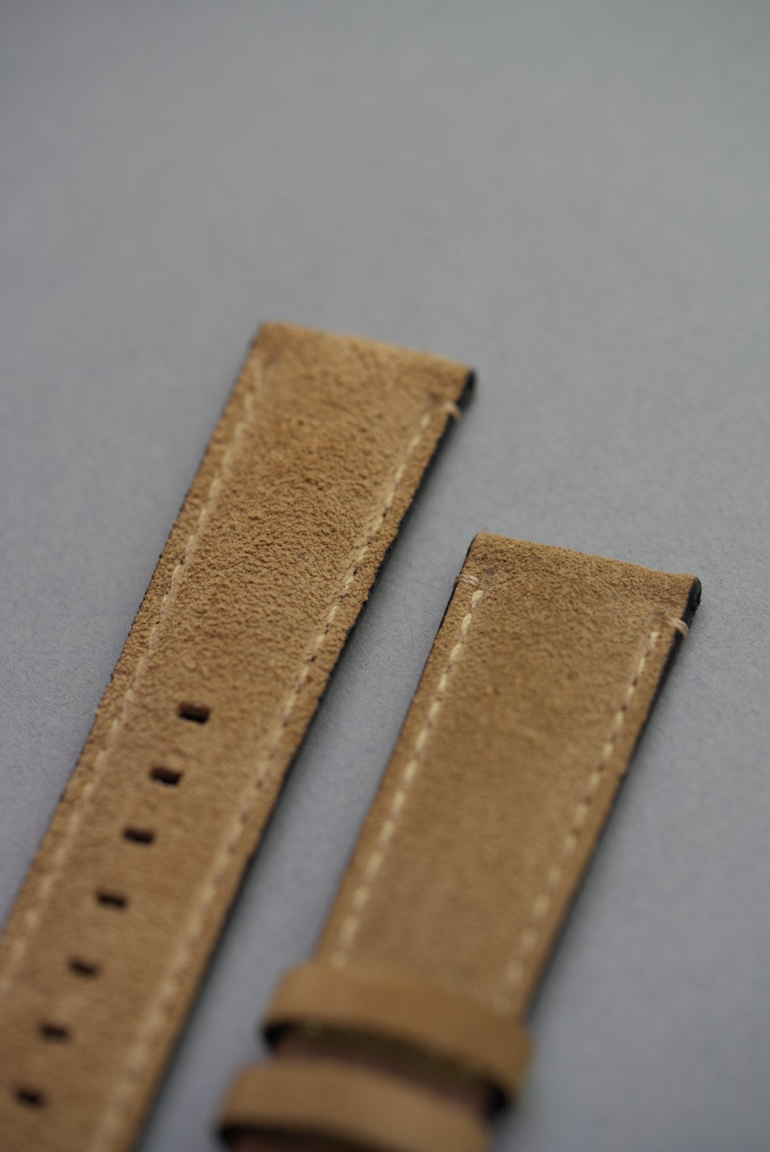 Detailed view of suede grain, stitching and edge finish on stone watch strap for replacement
