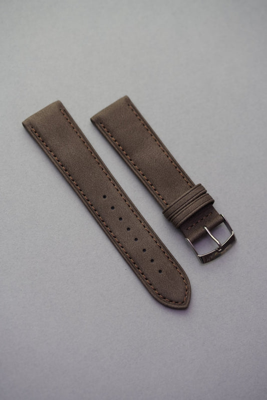 Dark brown suede watch strap laid flat showing clean stitching and buckle.