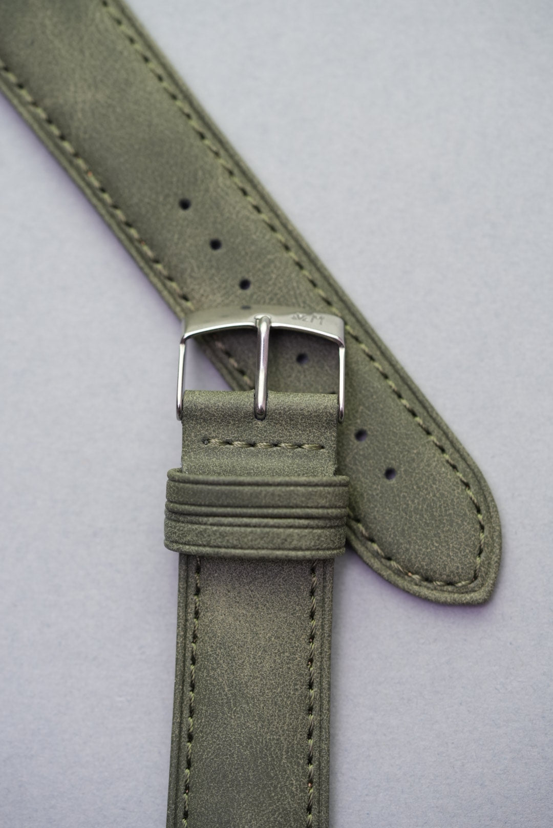 Detailed top-end view of olive green suede strap showing texture and stitching.
