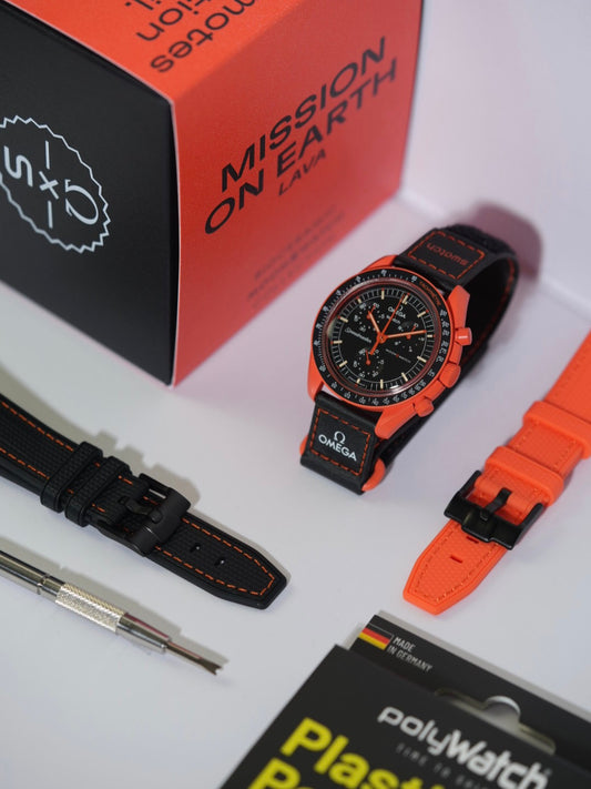 Swatch x Omega MoonSwatch Mission on Earth Lava watch displayed on a stand, featuring a bold orange bioceramic case with a black dial and tachymeter bezel. The watch is paired with a black strap with orange stitching, while additional strap options in black and orange are arranged alongside. A spring bar tool and a PolyWatch Plastic Polish kit are also included, with the original 'Mission on Earth Lava' packaging box in the background