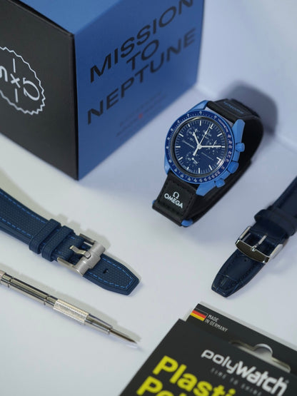 Swatch x Omega MoonSwatch Mission to Neptune watch displayed on a stand, featuring a deep blue bioceramic case and bezel with a black strap. The setup includes a blue stitched strap, a black leather strap with blue stitching, a spring bar tool, and a PolyWatch Plastic Polish kit. The original 'Mission to Neptune' packaging box is in the background.