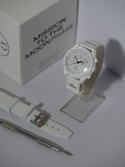 Swatch x Omega MoonSwatch Mission to the Moonphase bundle featuring the Moonphase watch, a white rubber strap, and a spring bar tool, displayed with its packaging.