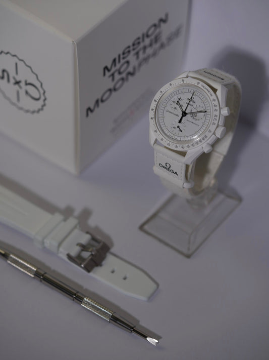 Swatch x Omega MoonSwatch Mission to the Moonphase bundle featuring the Moonphase watch, a white rubber strap, and a spring bar tool, displayed with its packaging.