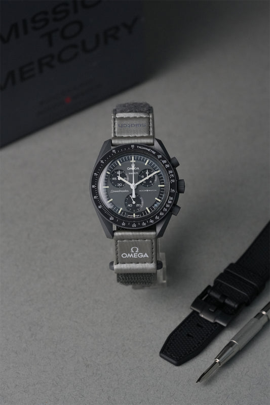 Swatch x Omega Mercury MoonSwatch with grey strap on a grey surface, with 'Mission to Mercury' text in the background.