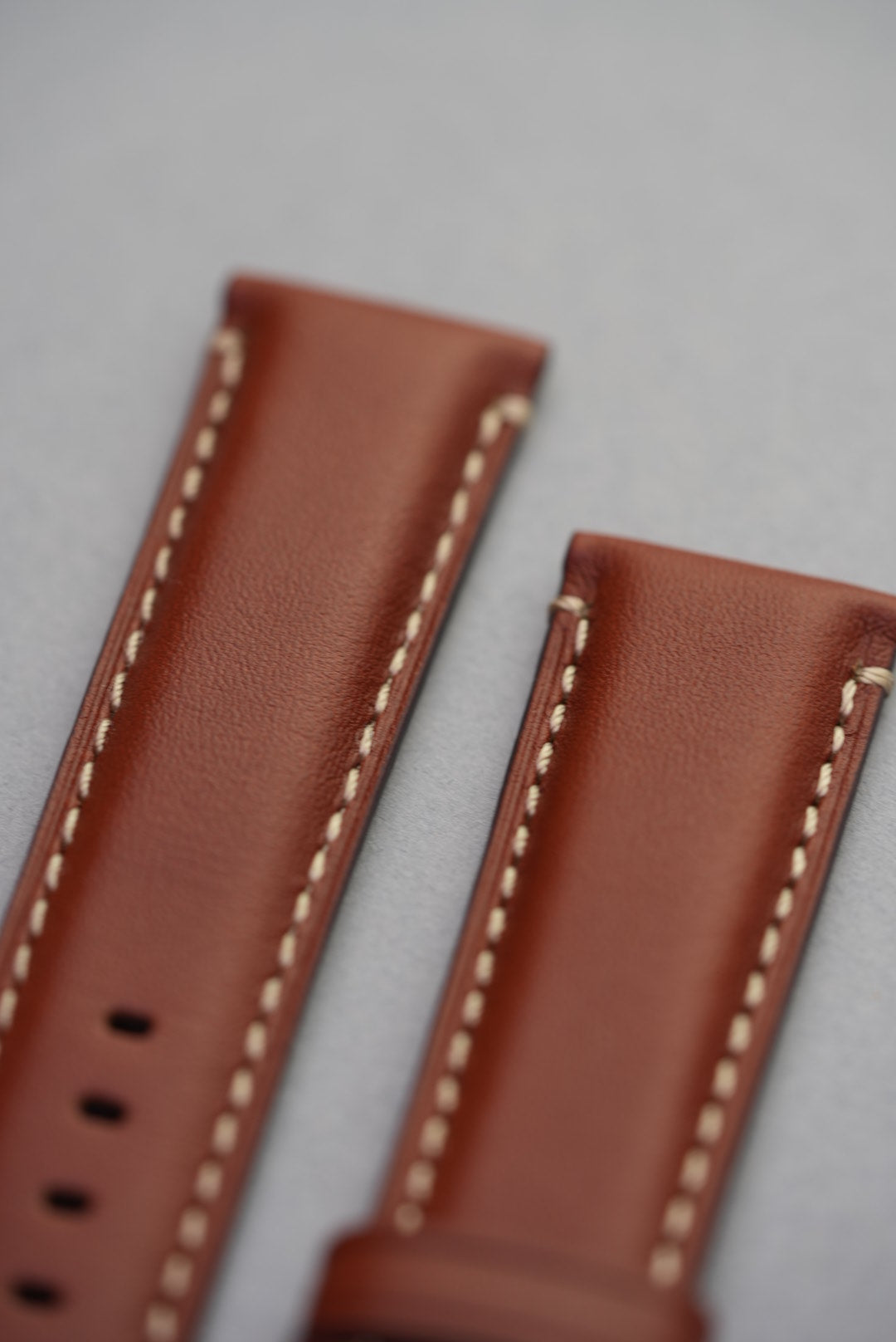 Angled view of tan leather strap showing front stitch and lug end detail
