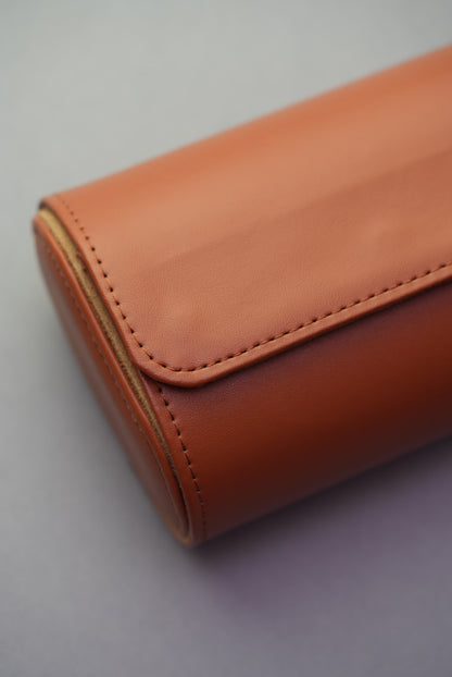 Close-up of stitching and end detail on closed three-slot tan watch roll.