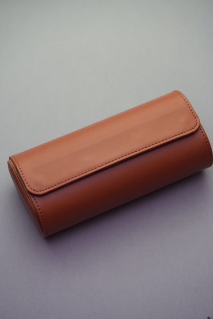 Three-slot travel watch roll in tan vegan leather shown closed from an angled top view.