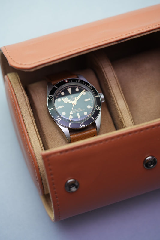 Tan travel watch roll opened with Tudor Black Bay watch resting in one of the suede-lined slots.