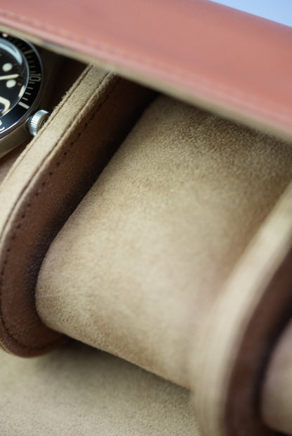 Side view of open tan watch roll showing all three suede-lined slots with one watch in position.