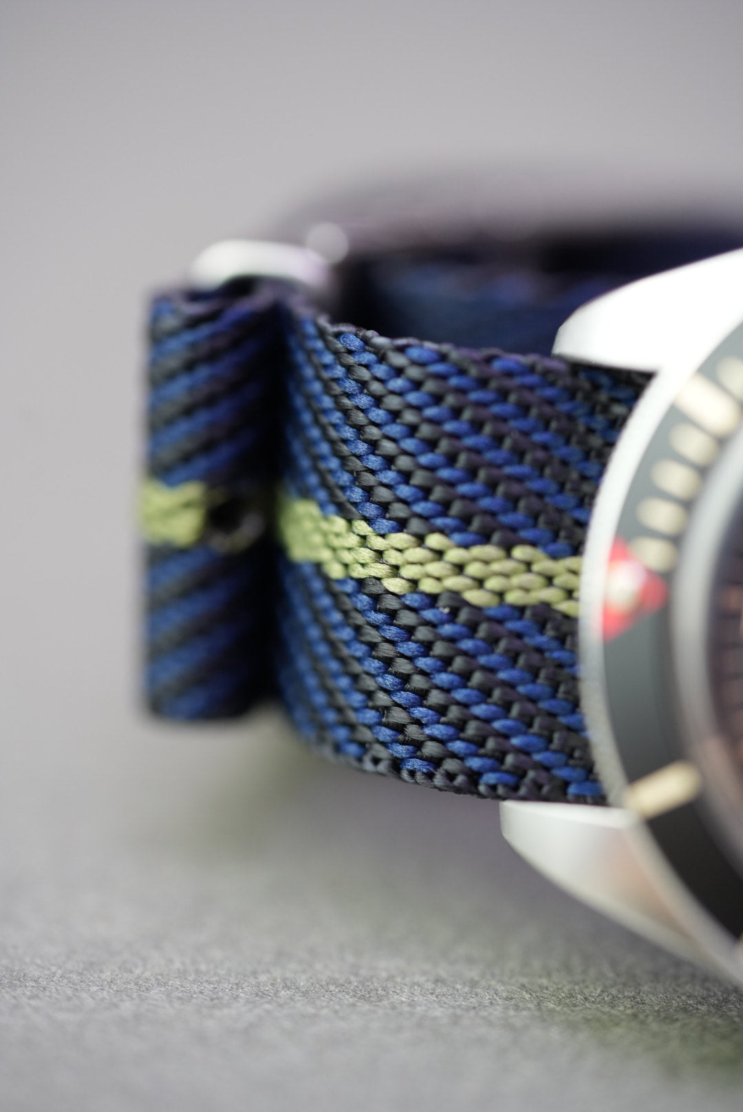 Macro detail of the yellow stripe and woven texture on navy nylon strap attached to a Tudor Black Bay.